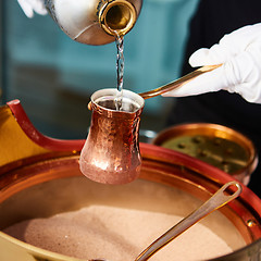 Image showing Preparation of Turkish coffee in the cezve in the sand at cafe bar