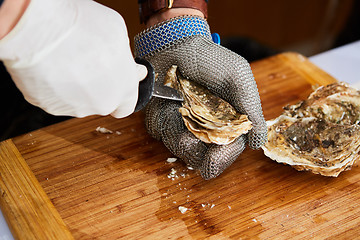 Image showing Fresh oyster held open with knife in hand