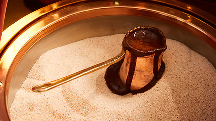 Image showing Preparation of Turkish coffee in the cezve in the sand at cafe bar