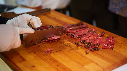 Image showing Butcher cutting slices of fresh beef
