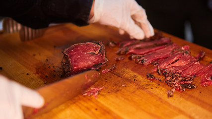 Image showing Butcher cutting slices of fresh beef