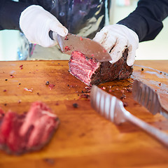 Image showing Butcher cutting slices of fresh beef