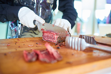 Image showing Butcher cutting slices of fresh beef