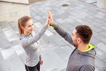 Image showing smiling couple making high five on city street