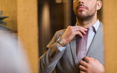 Image showing close up of man trying tie on at mirror