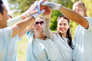 Image showing group of happy volunteers making high five in park