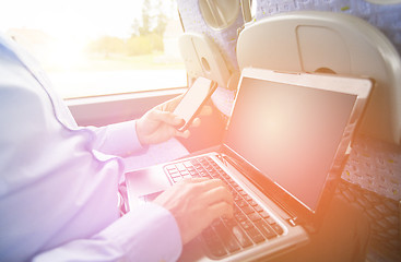 Image showing man with smartphone and laptop in travel bus