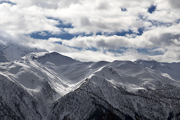 Image showing View on snowy mountains and sunlight cloudy sky in evening