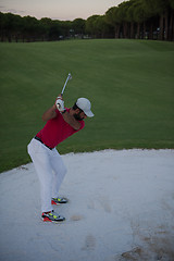 Image showing golfer hitting a sand bunker shot on sunset