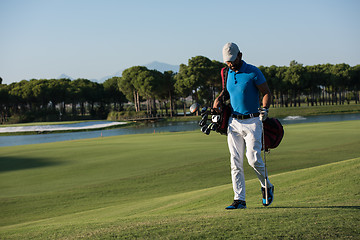 Image showing golf player walking and carrying bag