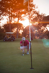 Image showing golf player aiming perfect  shot on beautiful sunset