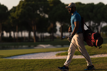 Image showing golfer  walking and carrying golf  bag at beautiful sunset