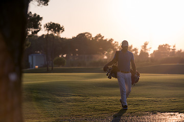 Image showing golfer  walking and carrying golf  bag at beautiful sunset