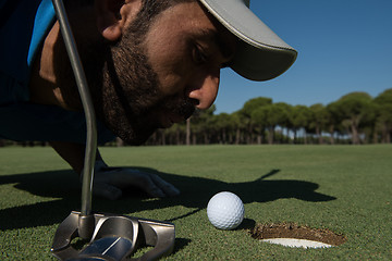 Image showing golf player blowing ball in hole