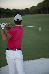 Image showing golfer hitting a sand bunker shot on sunset