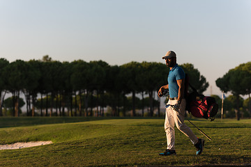 Image showing golfer  walking and carrying golf  bag at beautiful sunset