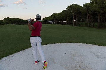 Image showing golfer hitting a sand bunker shot on sunset