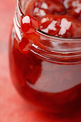 Image showing Strawberry jam blob over glass jar screw