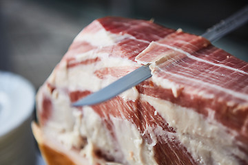 Image showing Chef slices serrano ham.