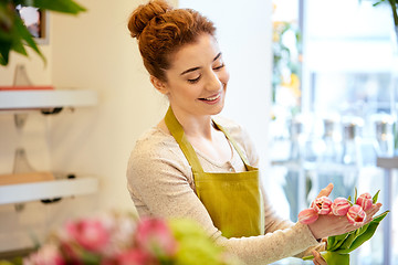 Image showing smiling florist woman making bunch at flower shop