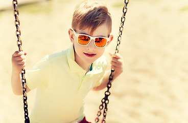 Image showing happy little boy swinging on swing at playground