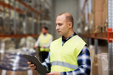 Image showing man with clipboard in safety vest at warehouse