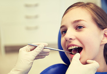 Image showing hands with dental mirror checking girl teeth