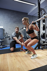 Image showing man and woman with bar flexing muscles in gym