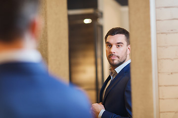 Image showing man trying jacket on at mirror in clothing store