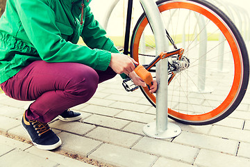 Image showing close up of man fastening bicycle lock on parking