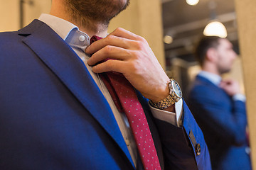 Image showing close up of man trying tie on at clothing store