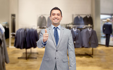 Image showing happy businessman in suit over clothing store