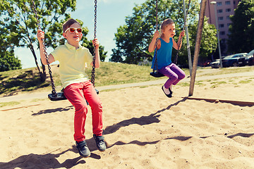 Image showing two happy kids swinging on swing at playground