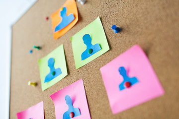 Image showing close up of paper human shapes on cork board
