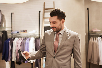 Image showing happy young man choosing bow-tie in clothing store