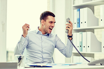 Image showing furious businessman calling on phone in office