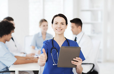 Image showing happy doctor with tablet pc over team at clinic