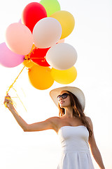 Image showing smiling young woman in sunglasses with balloons