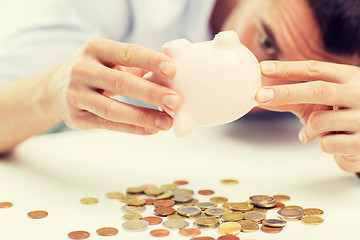 Image showing close up of man pouring coins from piggy bank