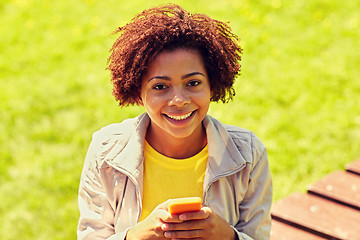Image showing happy african young woman messaging on smartphone