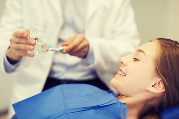 Image showing happy dentist showing jaw layout to patient girl