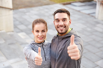 Image showing smiling couple showing thumbs up on city street