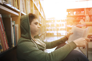 Image showing student boy or young man reading book in library