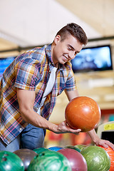 Image showing happy young man holding ball in bowling club