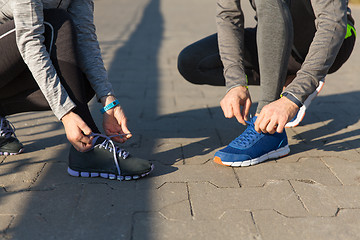 Image showing close up of couple tying shoelaces outdoors