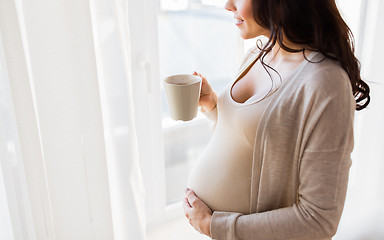 Image showing close up of pregnant woman with tea cup at window