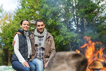 Image showing happy couple sitting on bench near camp fire