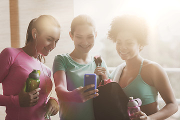 Image showing happy women with bottles and smartphone in gym