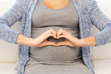 Image showing close up of happy pregnant woman making heart