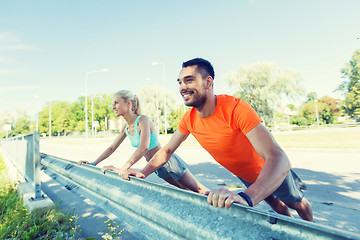 Image showing close up of happy couple doing push-ups outdoors